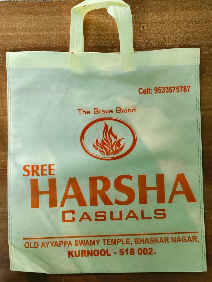 Light green non woven bag with sewn loop handles, printed in orange for a casual wear shop