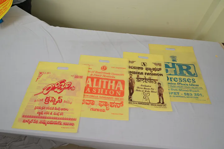 Four yellow non woven D-cut bags printed in red and green for readymade and fashion shops