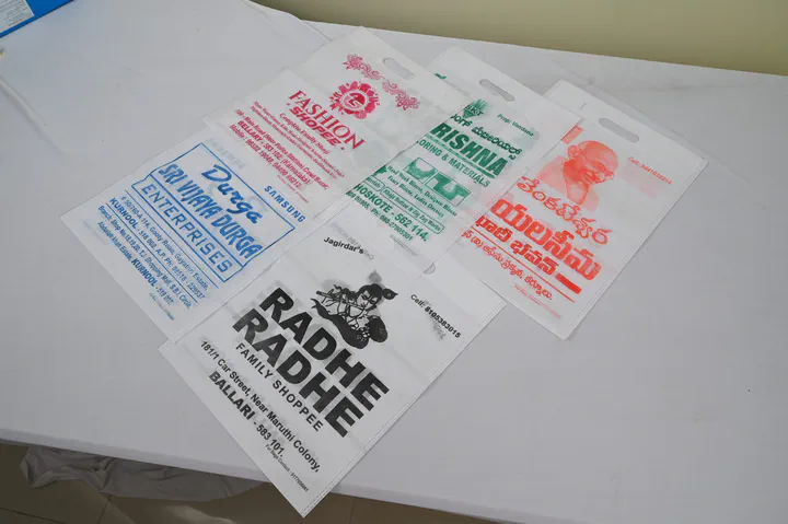 Six white non woven D-cut bags printed in one or two colours for textile, fashion and family shops