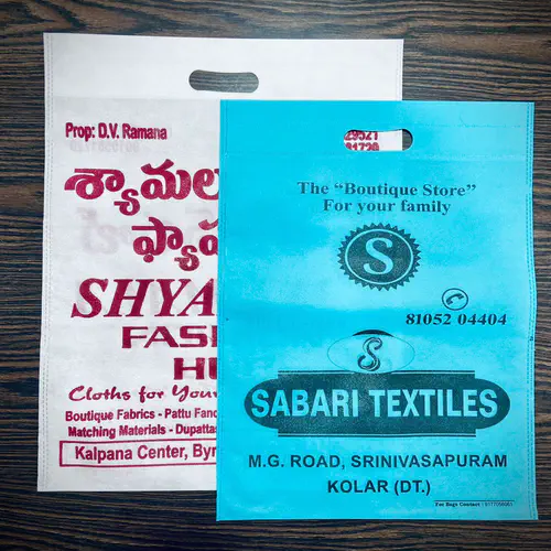 Two D-cut non woven bags, one white with maroon printing and one turquoise with black printing