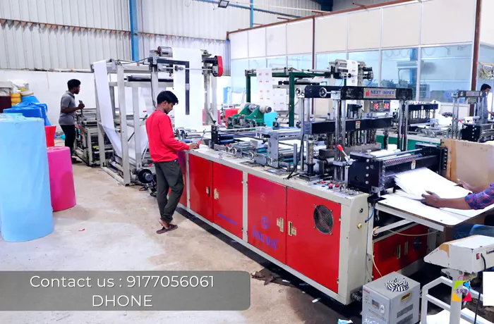 Automatic non-woven bag making machine in operation, with rolls of blue and pink non-woven fabric alongside