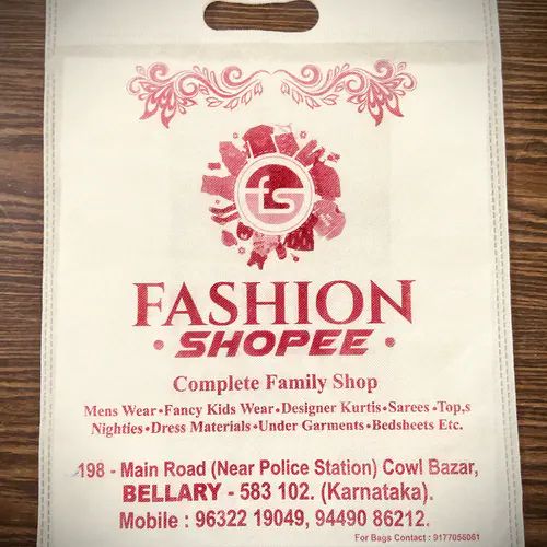 D-cut non woven carry bag in cream with red printing, made for a family clothing store in Bellary