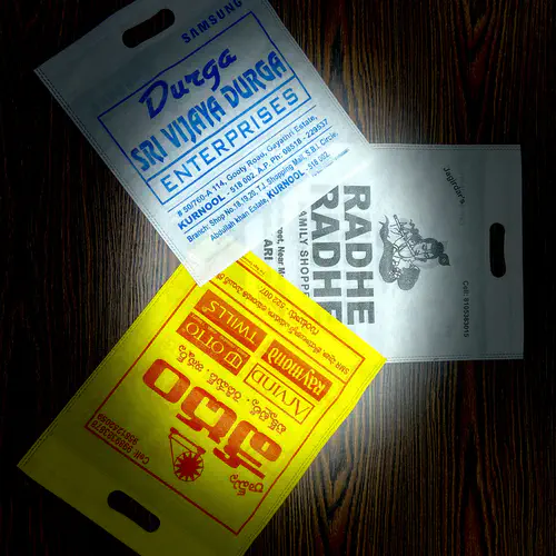 Three D-cut non woven carry bags in white and yellow with single colour printing, made for shops in Kurnool